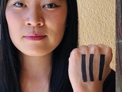 A woman holding up her hand, three marks drawn across it