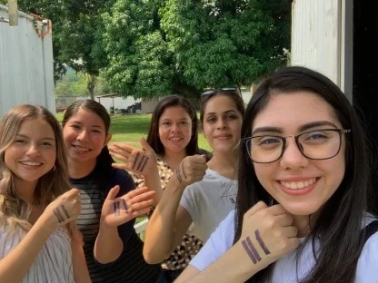 A group of friends outdoors, each showing the three marks