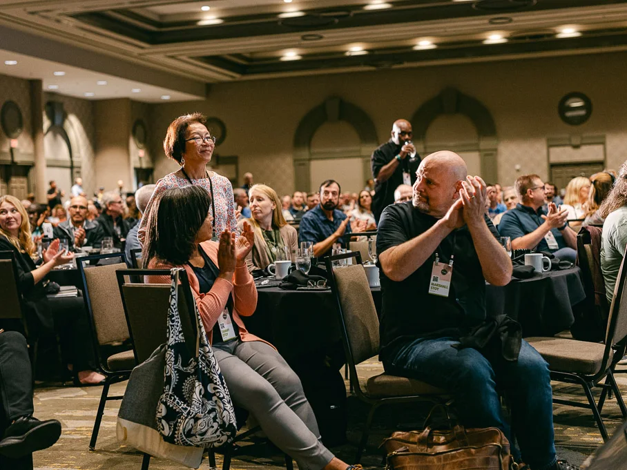 Conference attendees applauding from their tables during a Mission Leaders Conference session