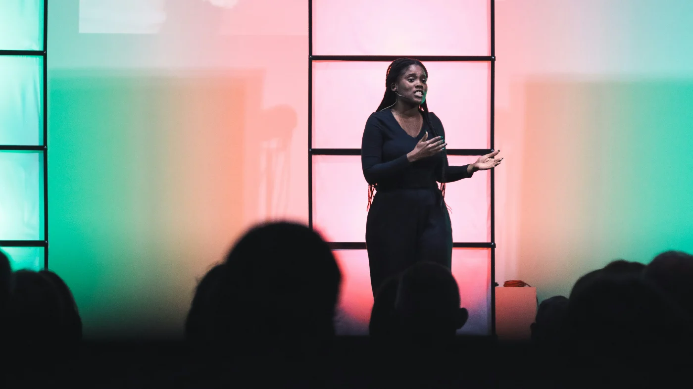 A speaker addressing an audience from the stage at a gathering