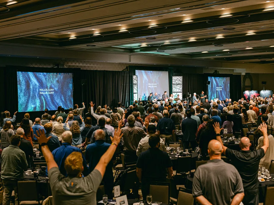 Attendees praying together, hands on shoulders, at a Missio Nexus gathering